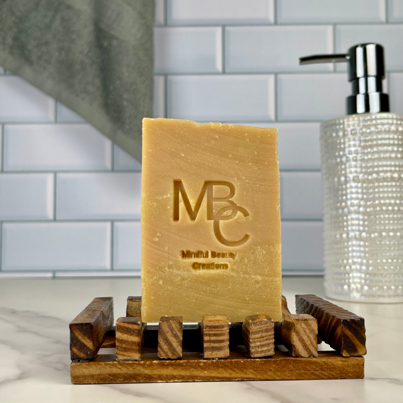 Bar of Island Drift soap on a wooden stand with 'MBC' branding in a bathroom setting.