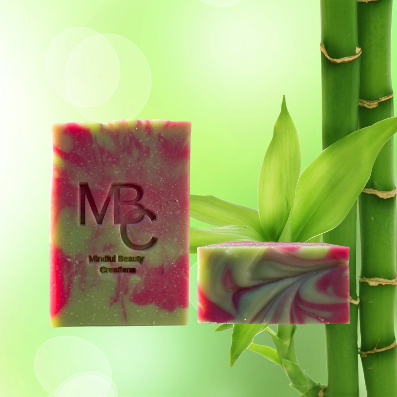 Close up of the front and top of a green and dark pink swirl pattern handmade bar soap. Fresh scent