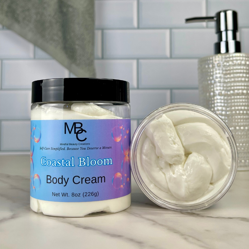 Coastal Bloom Body Cream jar with lid off on a marble surface, with a tiled wall background.