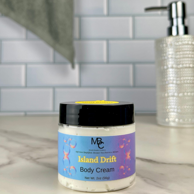 Jar of 'Island Drift' body cream on a bathroom counter with a tiled wall background