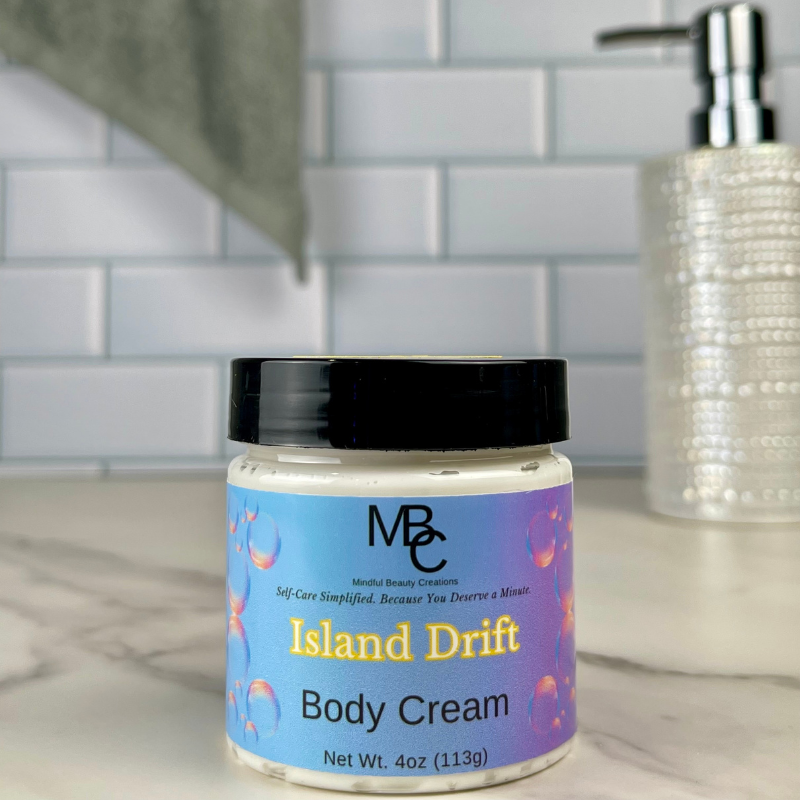 Jar of Island Drift Body Cream on a bathroom counter with soap dispenser in the background.