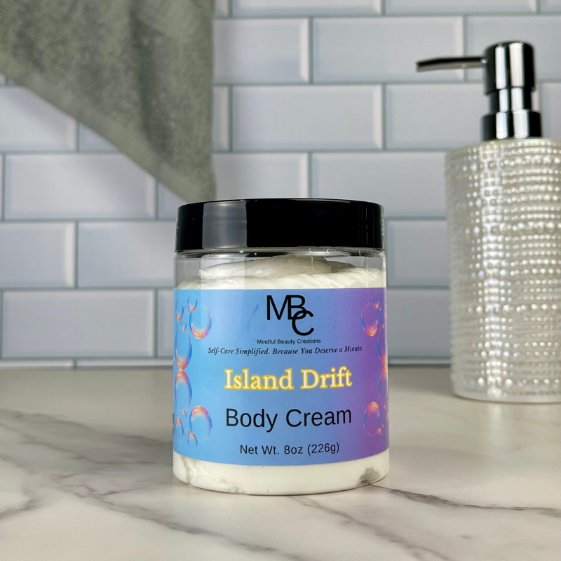 Jar of 'Island Drift' body cream with a purple label on a marble surface.