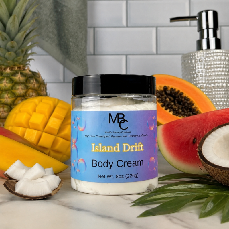 Jar of Island Drift Body Cream surrounded by tropical fruits and a dispenser on a marble surface.