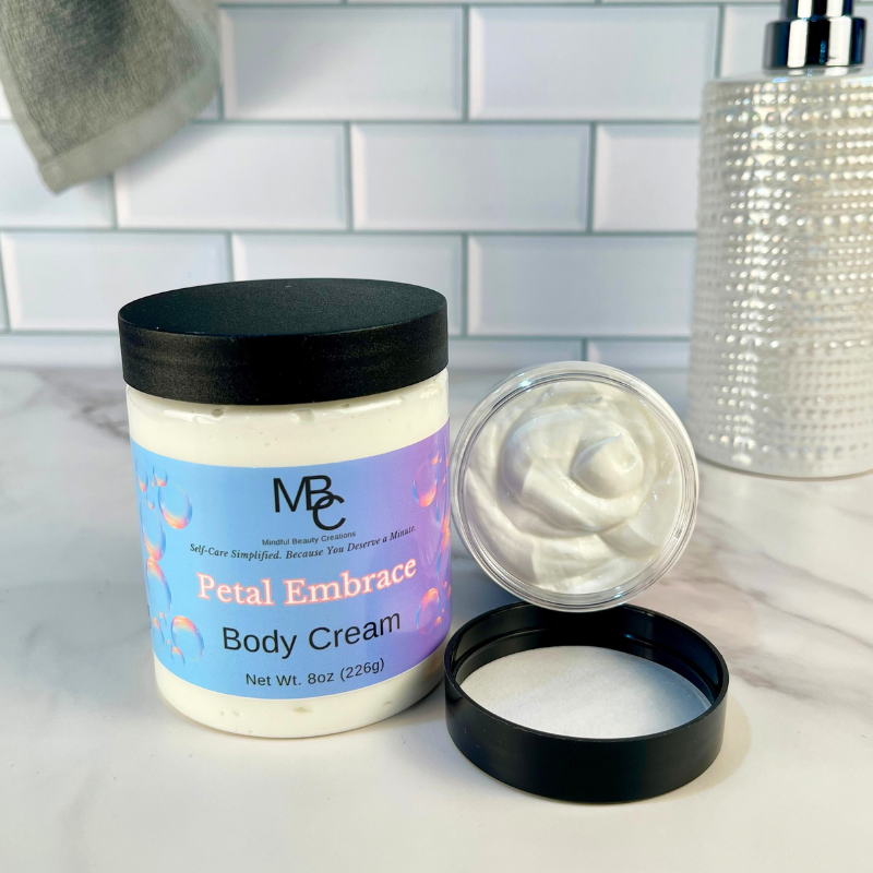 Body cream jar labeled Petal Embrace with open lid on a bathroom counter