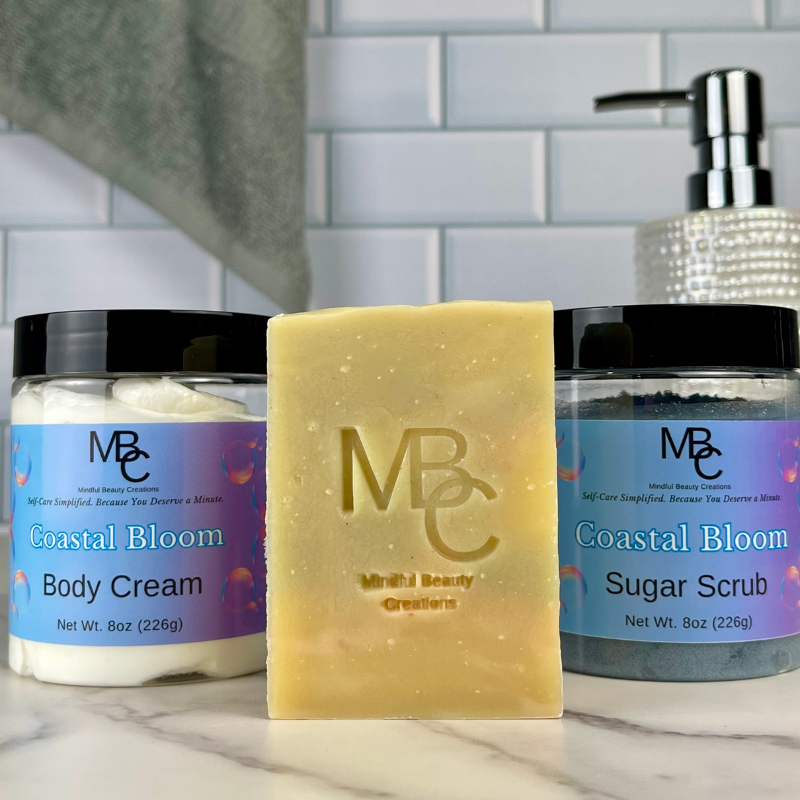 MBC Coastal Bloom body cream, soap, and sugar scrub on a marble surface with a tiled wall background