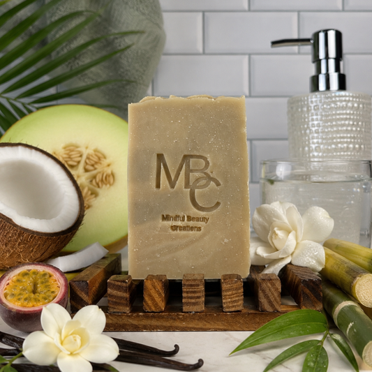 Bar of soap on a wooden stand with coconuts, flowers, and other natural elements on a marble surface.