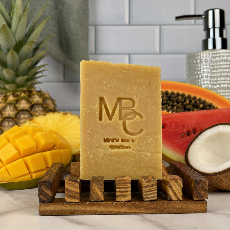 Bar of Island Drift soap with 'MBC' branding on a wooden stand, surrounded by fruits and a tiled wall.