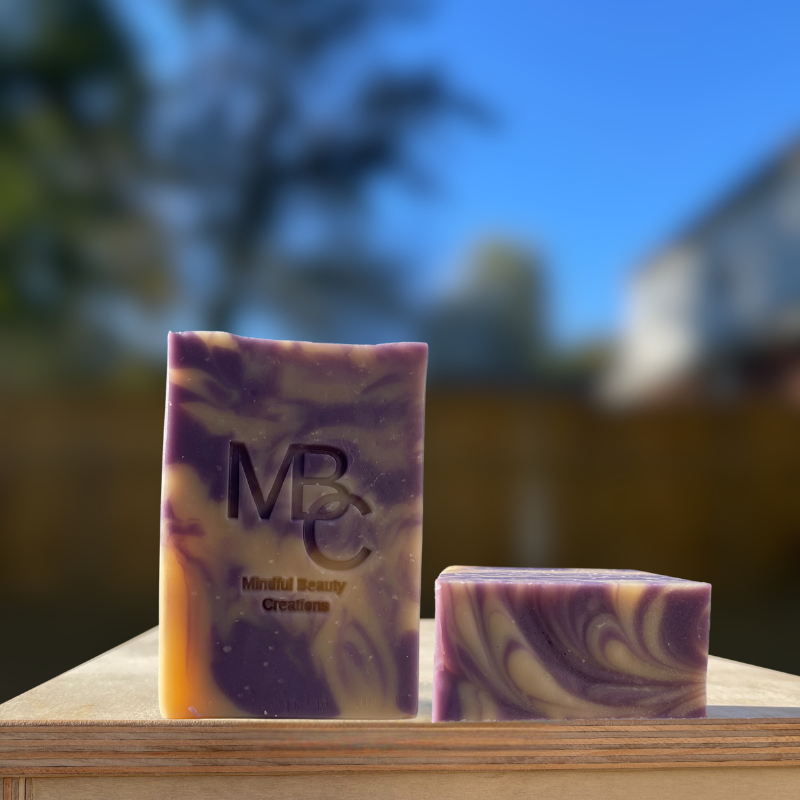 Close up of the front and top of a purple and tan swirl pattern handmade bar soap. Lavender and Chamomile scent