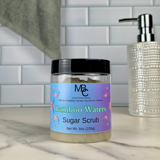 Jar of Bamboo Waters Sugar Scrub on a bathroom counter with soap dispenser in the background.