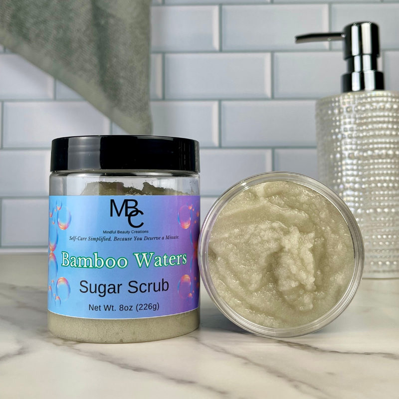 Bamboo Waters Sugar Scrub jar with open lid on a marble surface with a tiled wall background