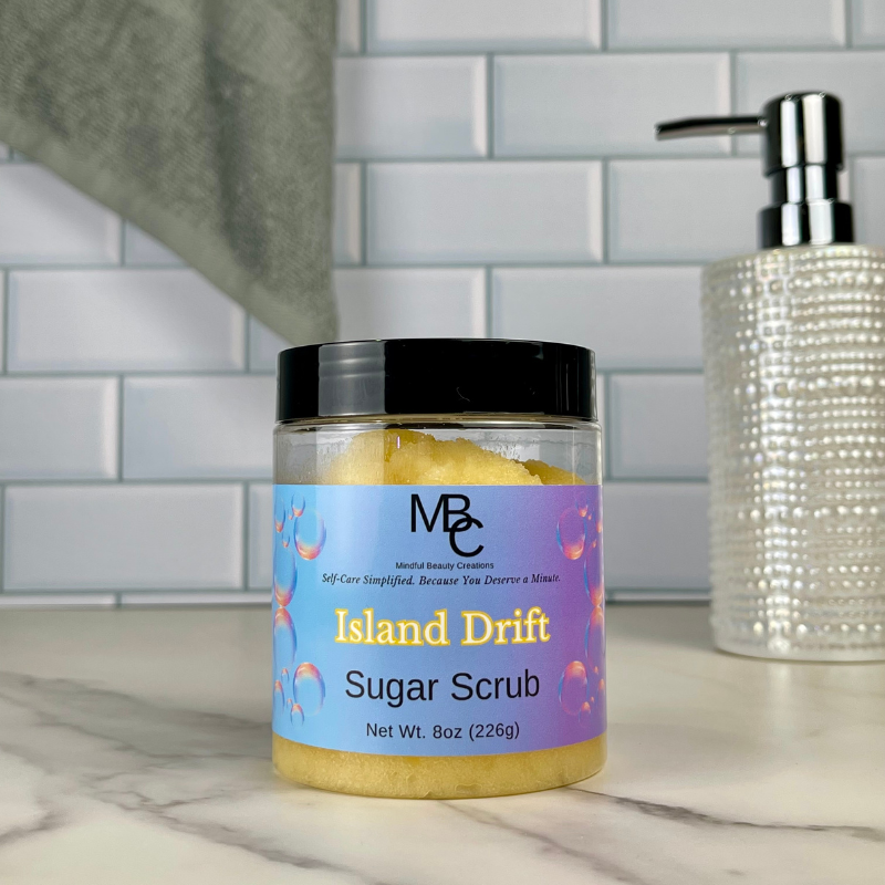 Jar of Island Drift Sugar Scrub on a bathroom counter with soap dispenser in the background.