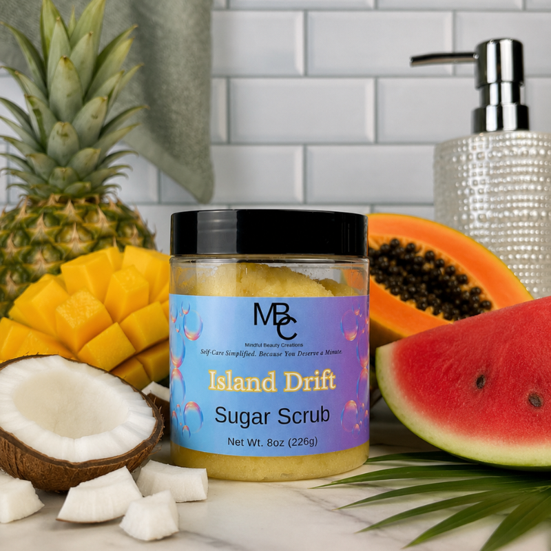 Jar of 'Island Drift' sugar scrub surrounded by tropical fruits on a white surface.
