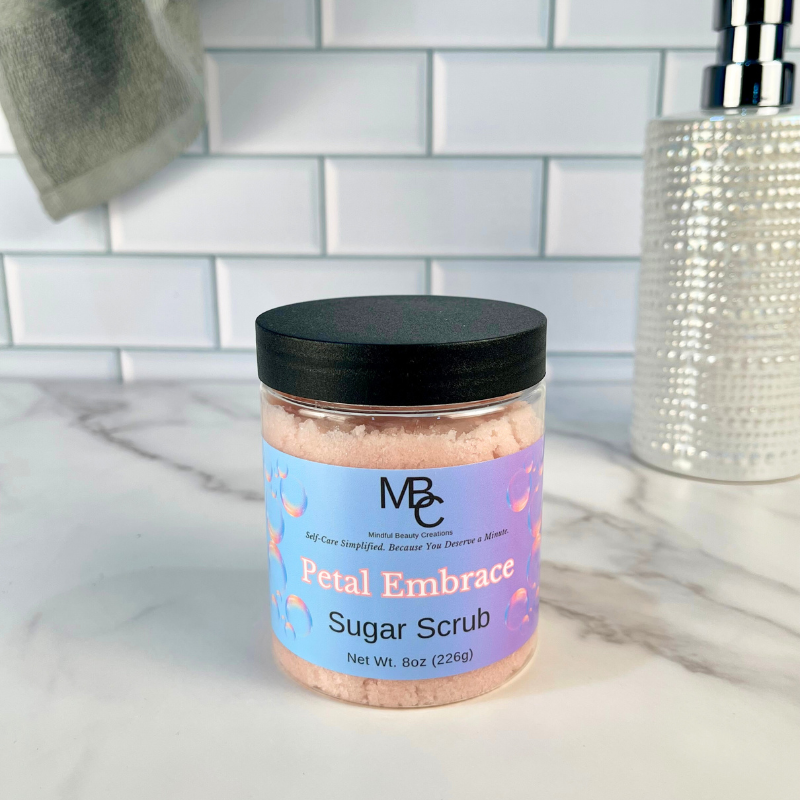 Jar of 'Petal Embrace' sugar scrub on a bathroom counter with a tiled wall background.