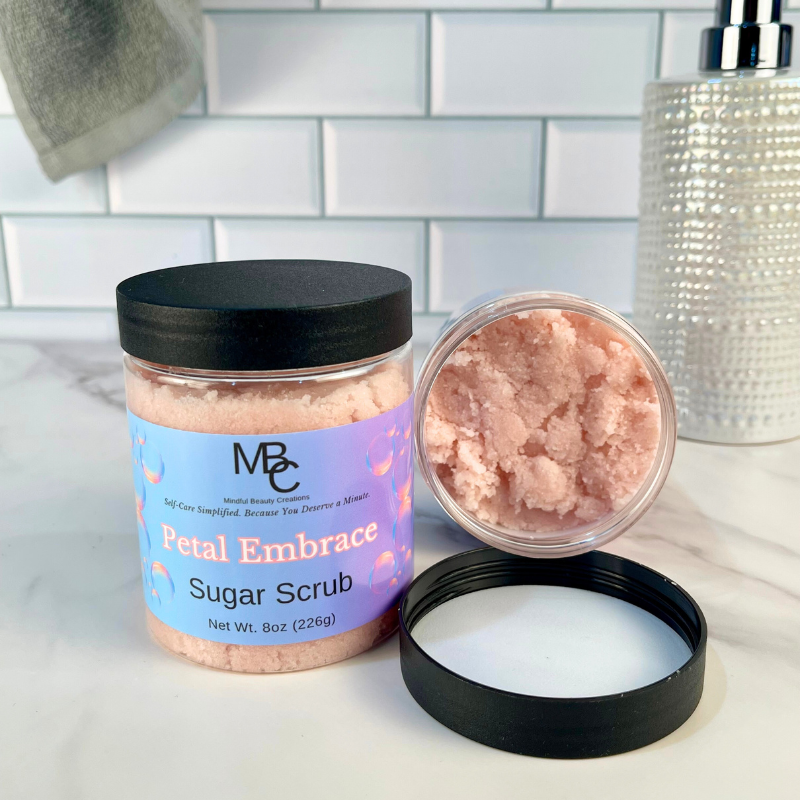 Petal Embrace Sugar Scrub jar with open lid on a bathroom counter.