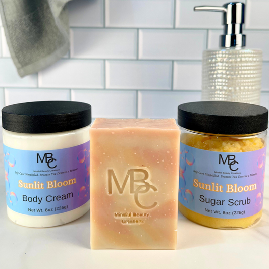 MBC skincare products including body cream, soap, and sugar scrub on a bathroom counter. All named Sunlit Bloom.